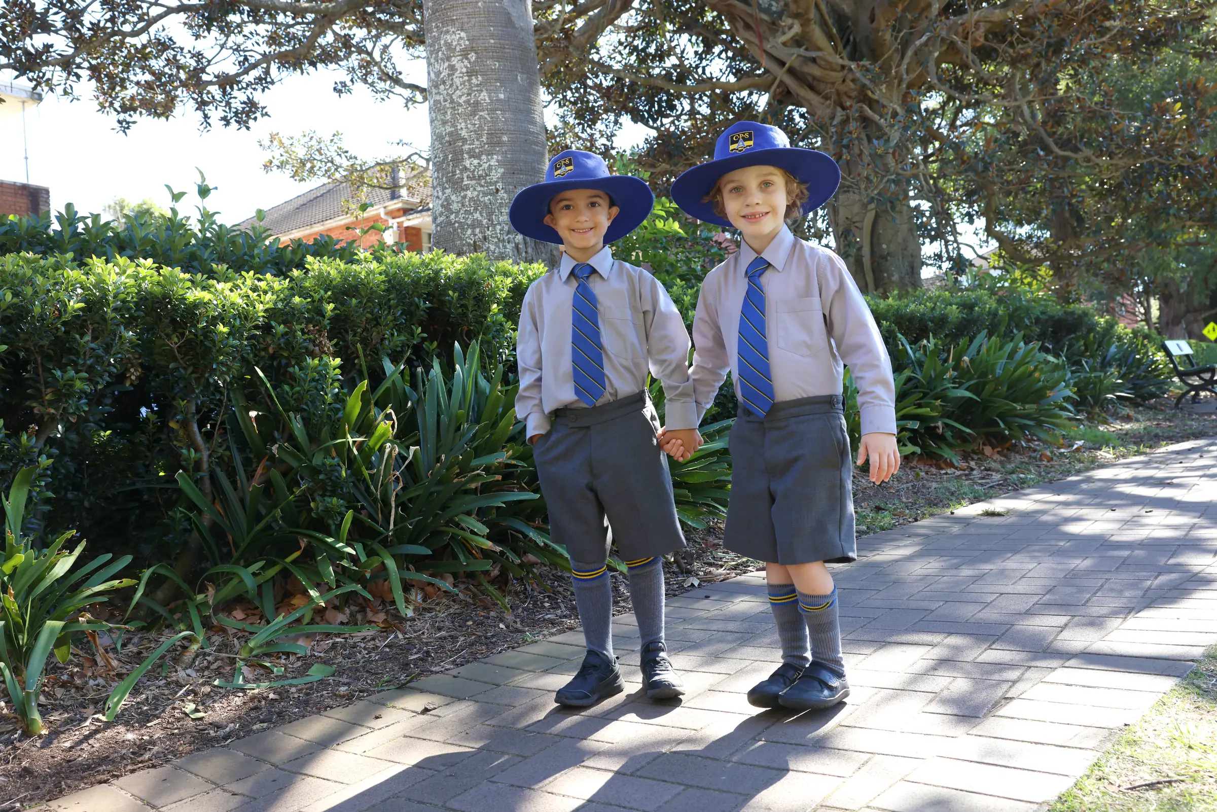 Two Coogee Prep boys in school hats walking through the school grounds