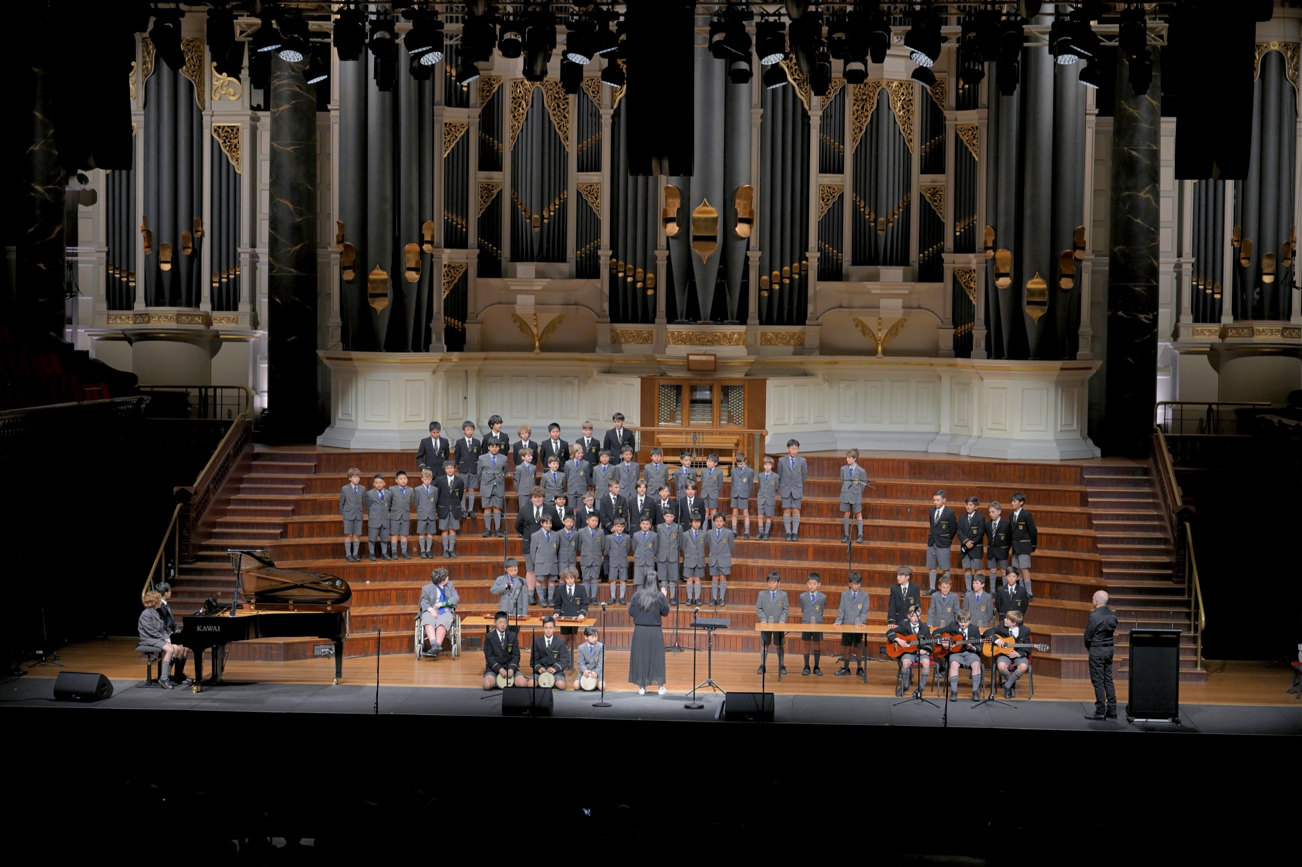 The Coogee Prep choir performing on stage in a concert hall in front of the pipe organ