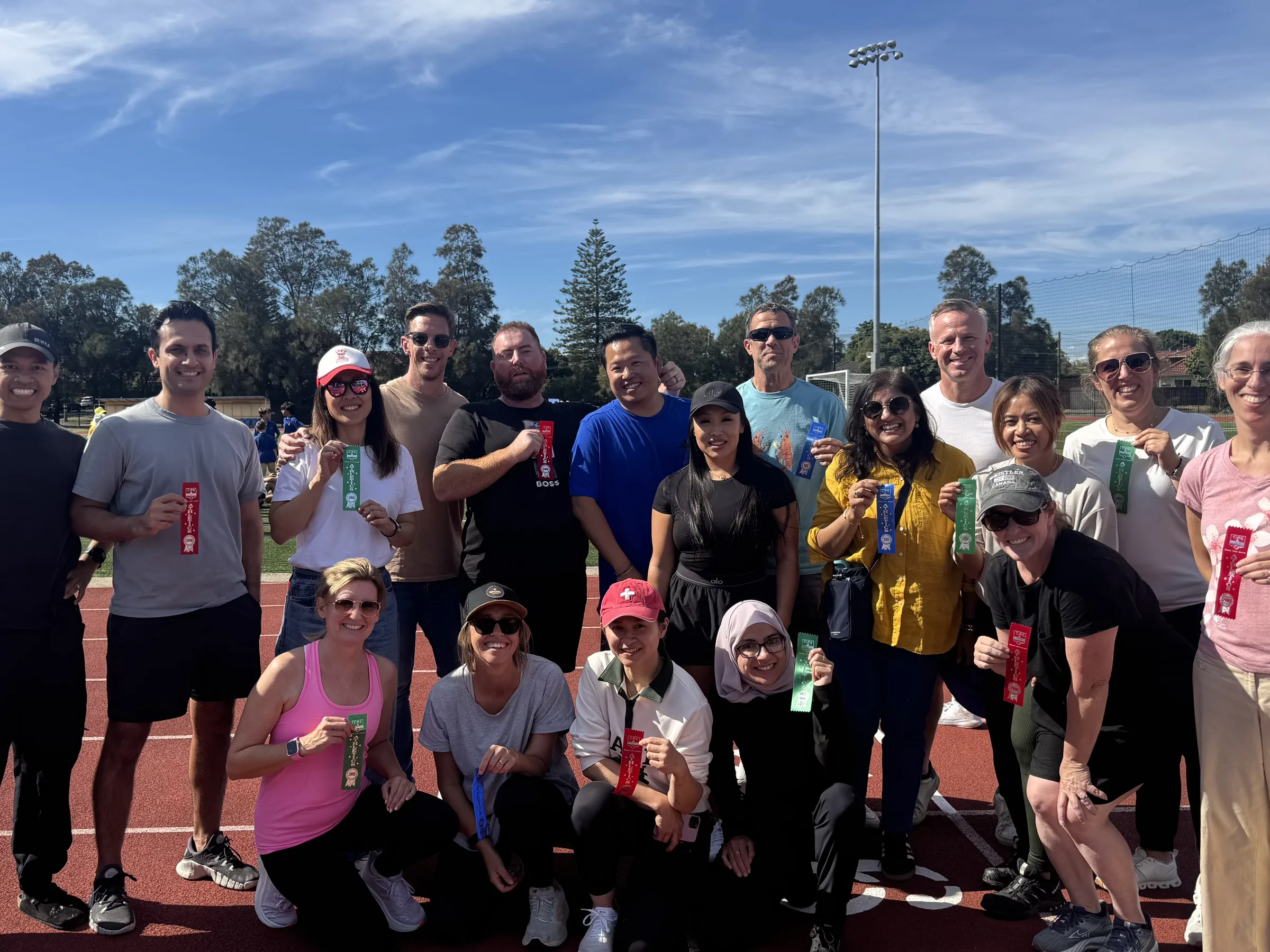 Coogee Prep Parents and Friends members holding place ribbons on the athletics track at a school carnival